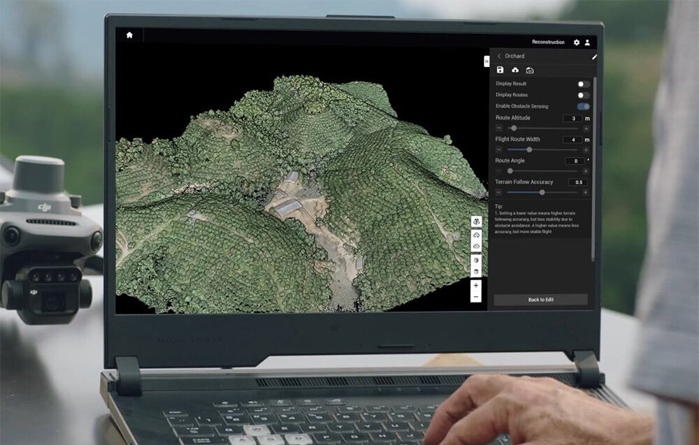 Osoba obsługuje laptopa, na ekranie którego wyświetlana jest trójwymiarowa mapa terenu z gęstą roślinnością. Obok laptopa znajduje się dron z widocznym logo DJI.