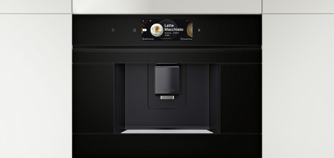 Czarny ekspres do kawy z wyświetlaczem pokazującym napis \'Latte Macchiato\'. Urządzenie ma nowoczesny design i wbudowany panel dotykowy.