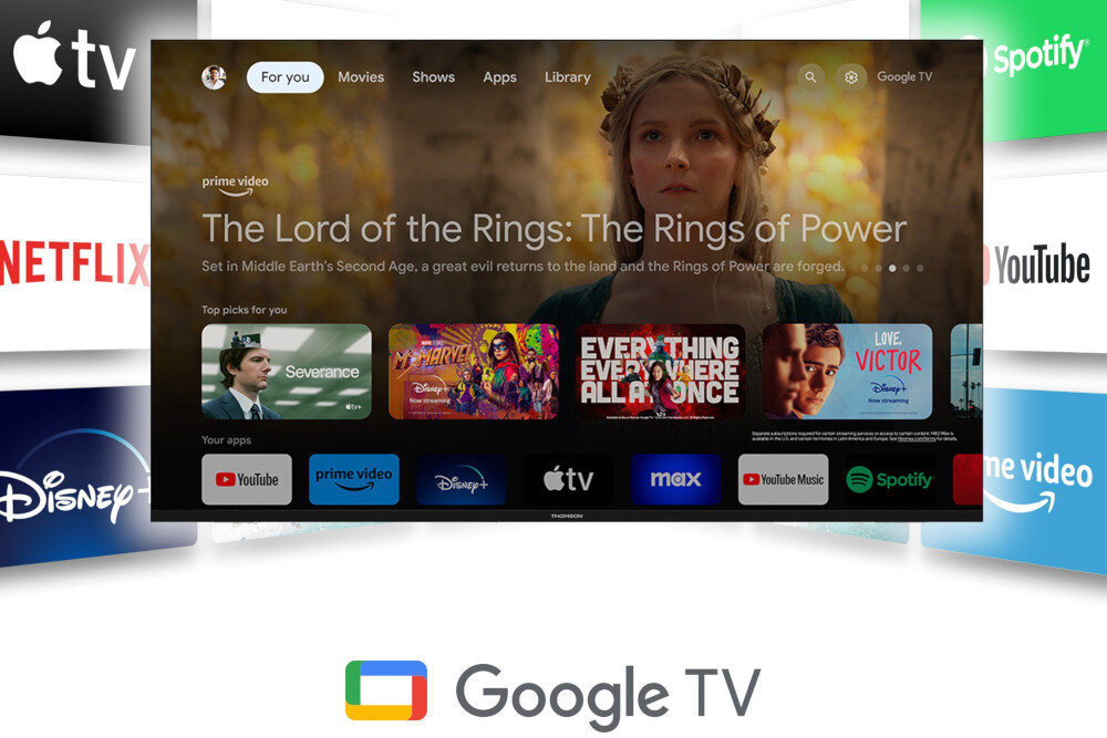 Ekran telewizora wyświetla interfejs Google TV z widocznymi aplikacjami takimi jak YouTube, Prime Video, Disney+, Apple TV, Max, YouTube Music i Spotify. Na ekranie widoczny jest także baner promujący serial \'The Lord of the Rings: The Rings of Power\'.