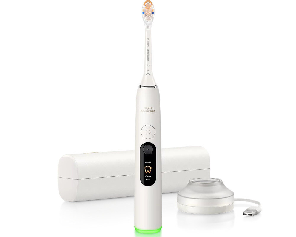 Biała szczoteczka soniczna z napisem \'Philips Sonicare\' na rączce, z przyciskiem zasilania i wyświetlaczem trybu \'Clean\'. Obok znajduje się etui podróżne i ładowarka indukcyjna z kablem USB.