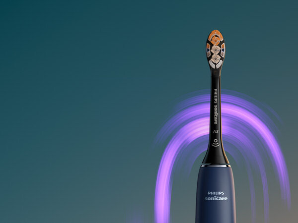 Szczoteczka soniczna z ciemnym uchwytem i kolorowymi włóknami na główce, z widocznym napisem \'PHILIPS sonicare\'. W tle widoczne są fioletowe smugi na ciemnym tle.