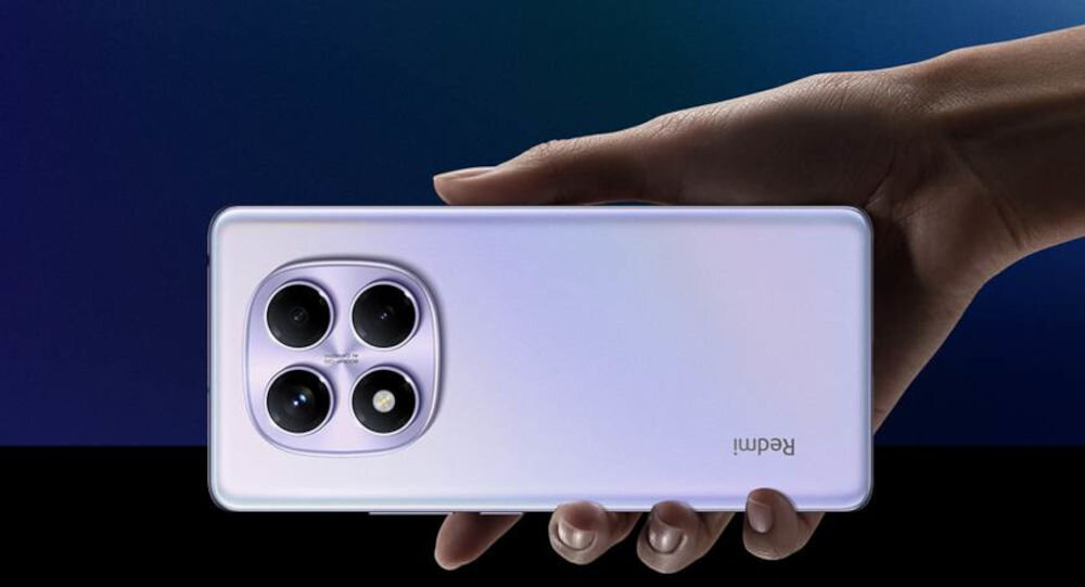 Osoba trzyma smartfon z czterema obiektywami aparatu na tylnej obudowie. Na obudowie widoczny jest napis \'Redmi\'.