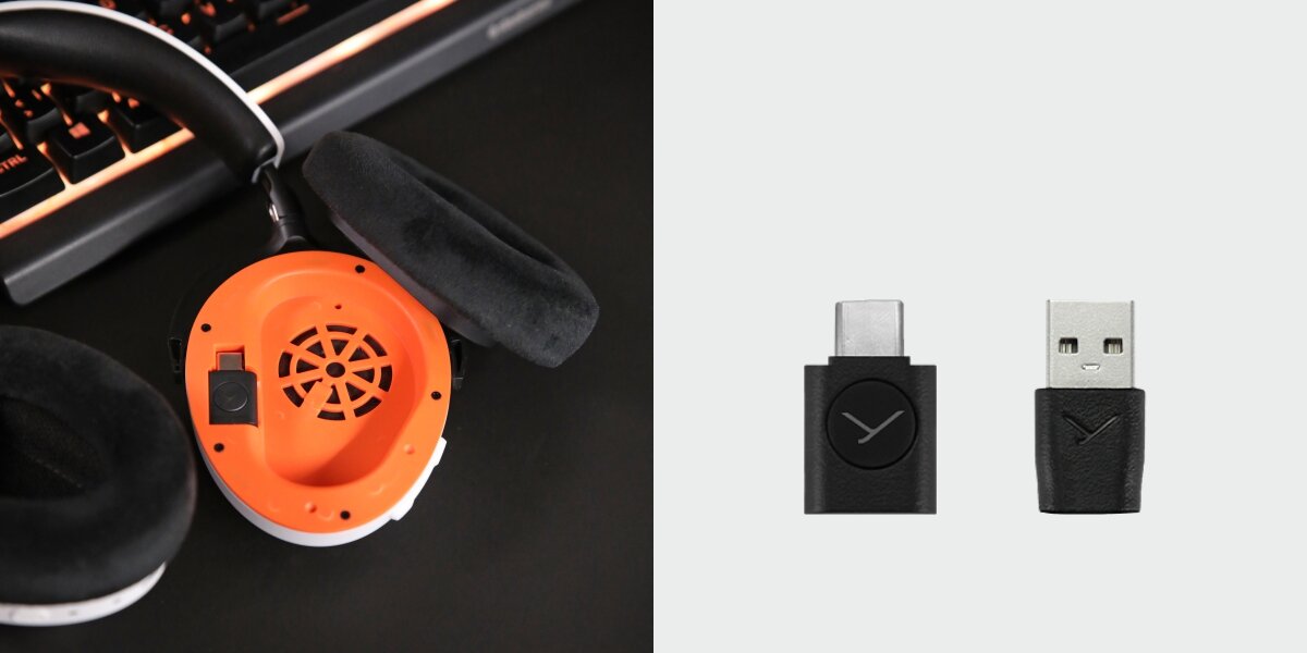 Na obrazie widoczne są słuchawki z pomarańczowym wnętrzem muszli oraz dwa adaptery USB z logo w kształcie litery \'Y\'.