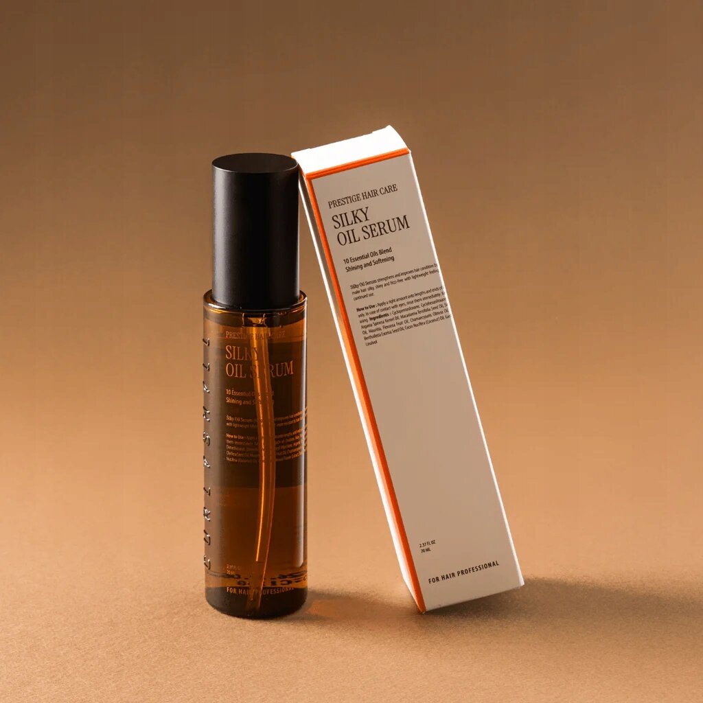 Na obrazie widoczna jest butelka z ciemnego szkła z czarną nakrętką oraz pudełko z napisem \'PRESTIGE HAIR CARE SILKY OIL SERUM\'. Tło jest jednolite, w odcieniach brązu.