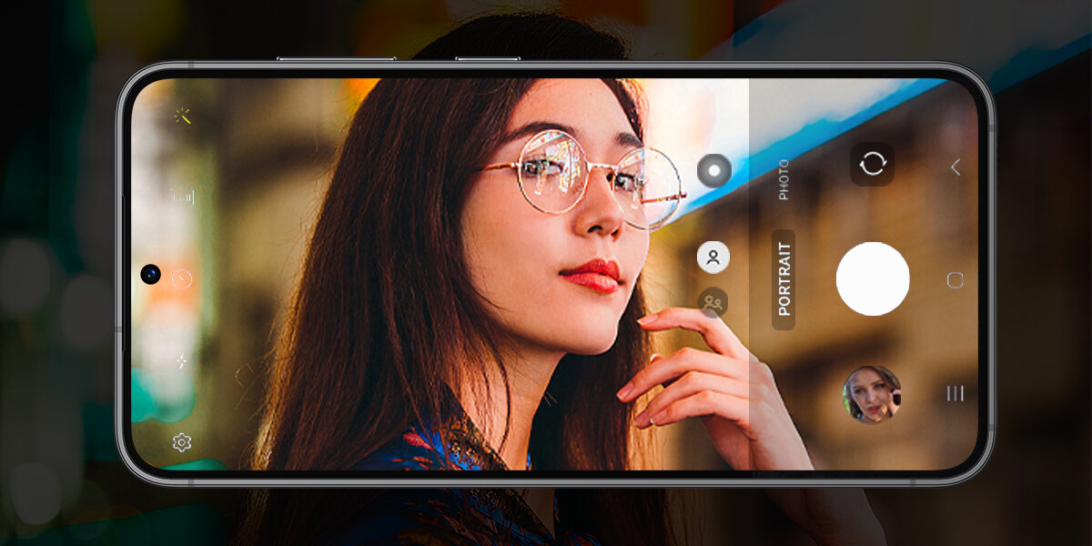 Smartfon wyświetla zdjęcie kobiety w okularach na ekranie w trybie portretowym. Na ekranie widoczne są ikony aparatu i ustawień trybu fotograficznego.