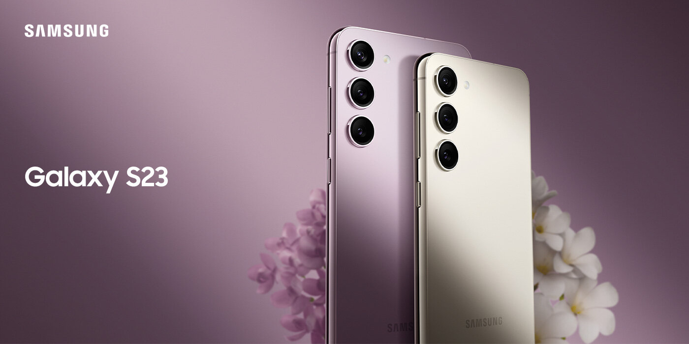 Dwa smartfony z trzema aparatami z tyłu, ustawione na tle z kwiatami. Widoczny tekst: \'SAMSUNG Galaxy S23\'.