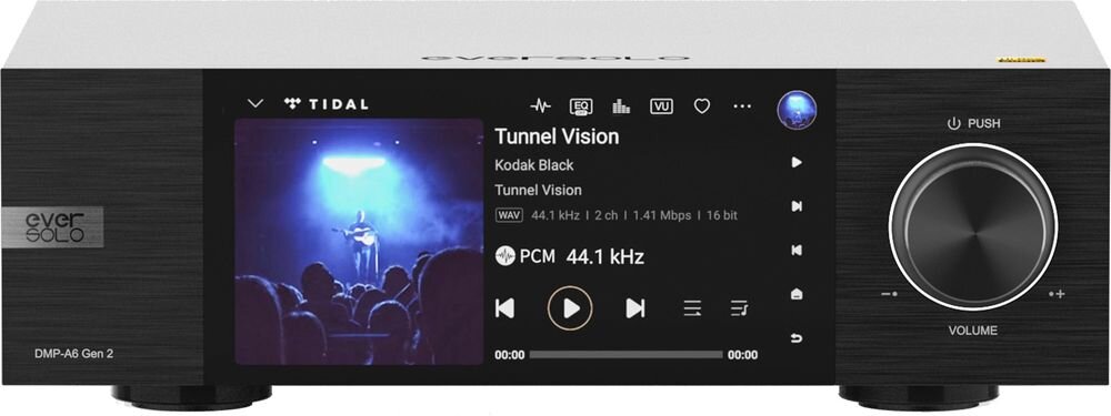 Na obrazie widoczny jest czarny odtwarzacz sieciowy z wyświetlaczem pokazującym interfejs aplikacji TIDAL, odtwarzający utwór \'Tunnel Vision\' przez Kodak Black. Po prawej stronie znajduje się duże pokrętło z napisem \'VOLUME\'.