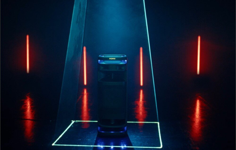 Na obrazie widoczny jest głośnik marki SONY ustawiony na podświetlonej podłodze, otoczony neonowymi liniami i czerwonymi światłami w tle. Głośnik ma nowoczesny design z podświetleniem na dole.