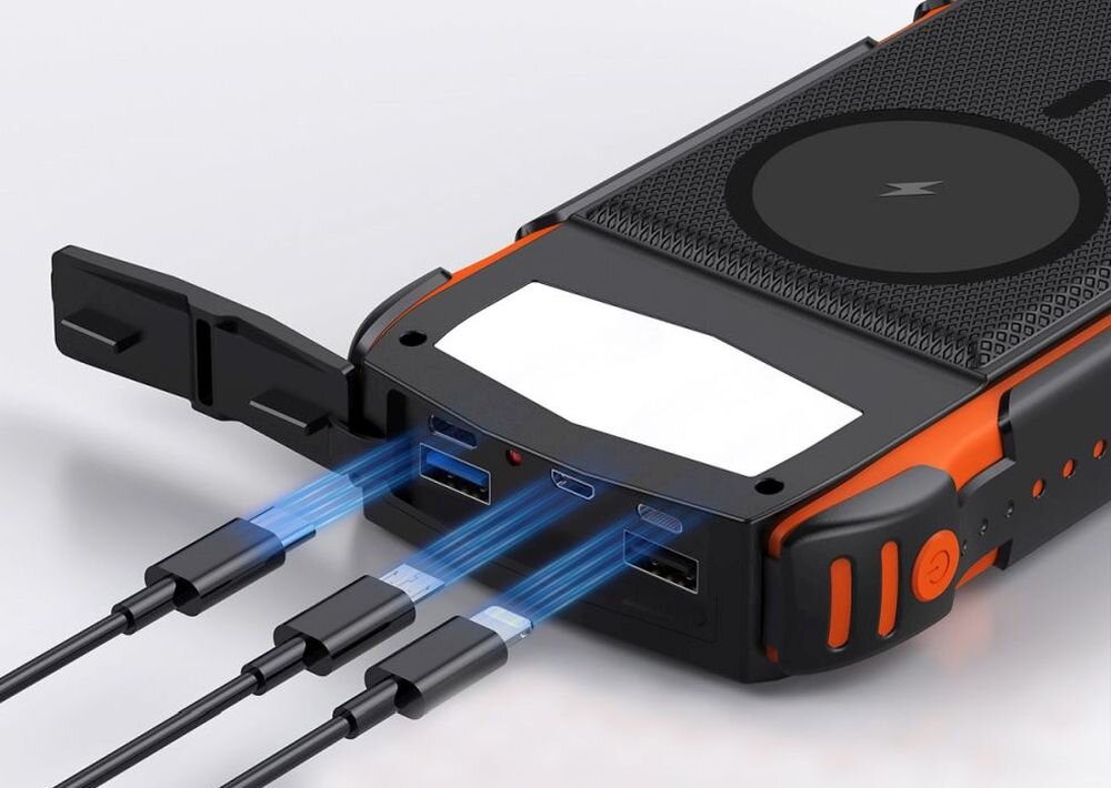 Powerbank z trzema podłączonymi kablami, posiada czarną obudowę z pomarańczowymi elementami i okrągłym symbolem na powierzchni. Widoczne są różne porty do ładowania oraz przycisk zasilania.