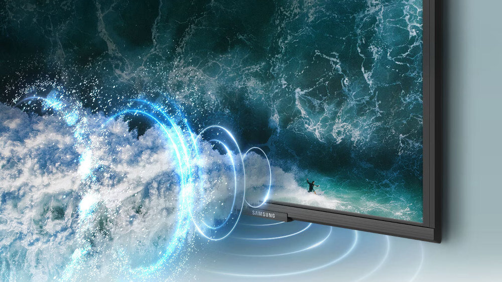 Telewizor wyświetla obraz z falami oceanu, a z jego dolnej krawędzi wychodzą niebieskie kręgi symbolizujące dźwięk. Na ramce telewizora widoczne jest logo \'SAMSUNG\'.