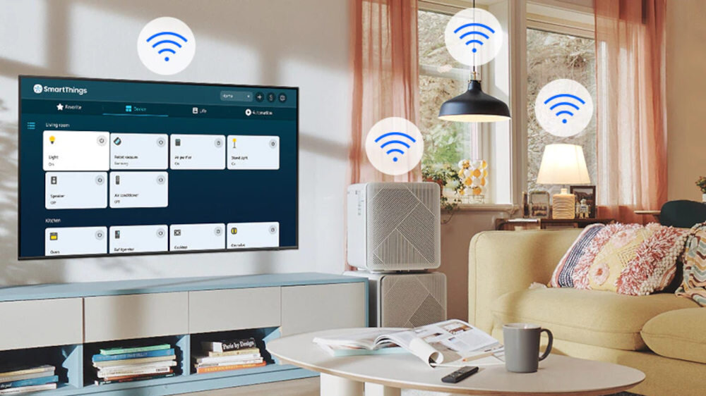 W salonie znajduje się telewizor z wyświetlonym interfejsem SmartThings, a wokół niego widoczne są ikony sygnału Wi-Fi. W pomieszczeniu jest również kanapa, stolik z pilotem i książkami oraz lampa sufitowa.