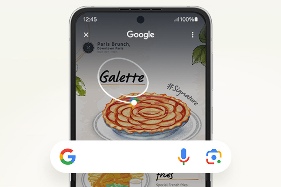 Na ekranie smartfona widoczna jest aplikacja Google z wyszukiwaniem obrazu przedstawiającego galette. Na dole ekranu znajdują się ikony Google, mikrofonu i aparatu.