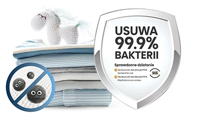Na obrazie widoczny jest stos złożonych ręczników z pluszowym jednorożcem na górze oraz tarcza z napisem \'USUWA 99.9% BAKTERII\'. Obok znajduje się symbol przekreślonych bakterii i tekst \'Sprawdzone działanie\'.