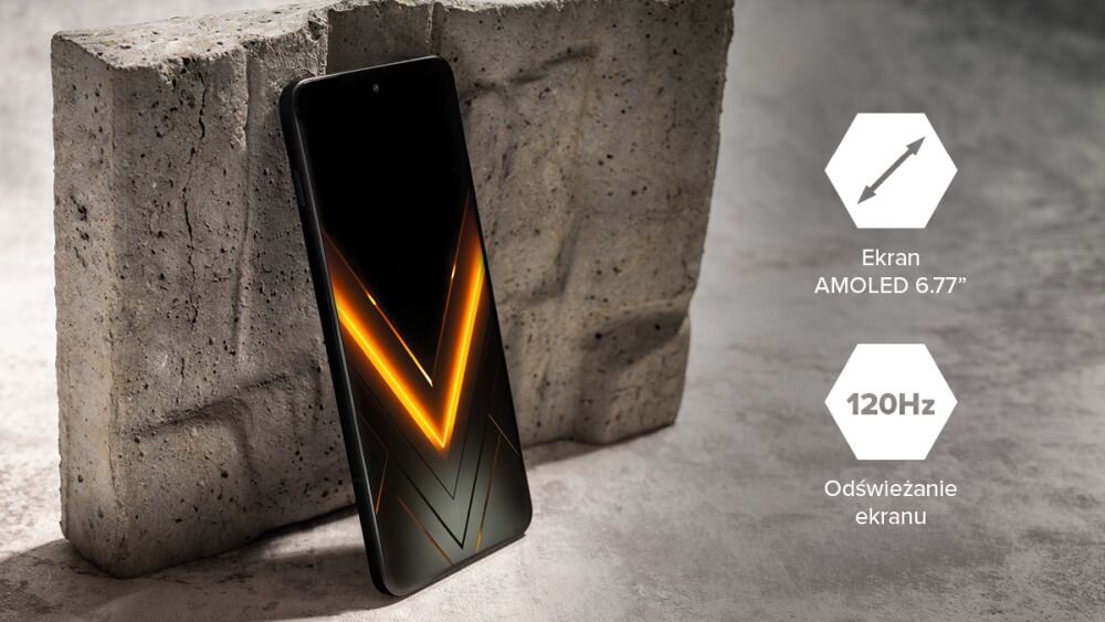 Smartfon z wyświetlaczem AMOLED 6.77 cala stoi oparty o betonowy blok. Obok widoczne są ikony z tekstem: \'Ekran AMOLED 6.77\' oraz \'120Hz Odświeżanie ekranu\'.