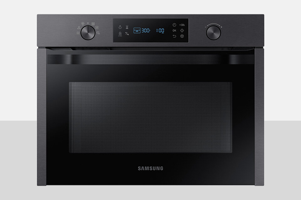 Mikrofala Samsung Czarny piekarnik z panelem sterowania z wyświetlaczem cyfrowym i dwoma pokrętłami. Na froncie widoczne jest logo \'SAMSUNG\'.