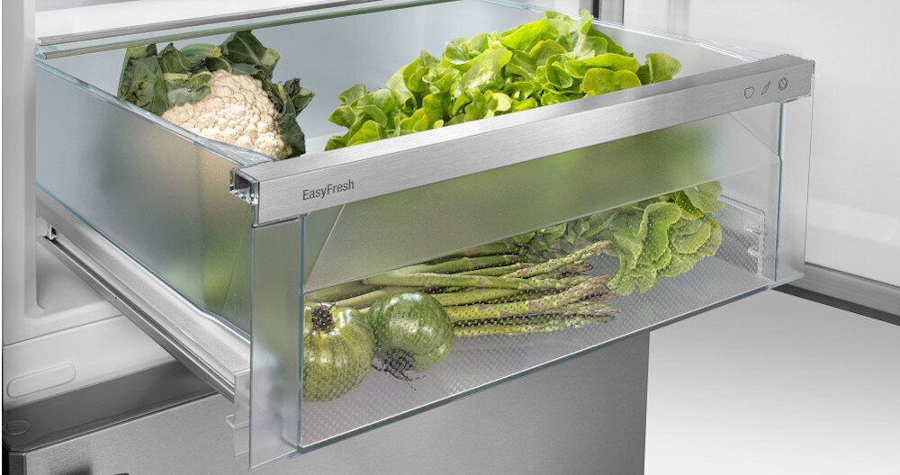 Szklana szuflada lodówki z napisem \'EasyFresh\', wypełniona warzywami takimi jak kalafior, sałata, szparagi i kapusta.