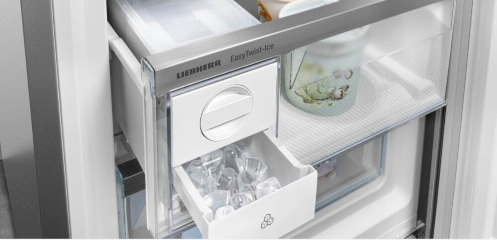 Wnętrze lodówki z widocznym pojemnikiem na lód z napisem \'EasyTwist-Ice\' oraz logo \'LIEBHERR\'. Pojemnik jest częściowo wysunięty, a w środku znajdują się kostki lodu.