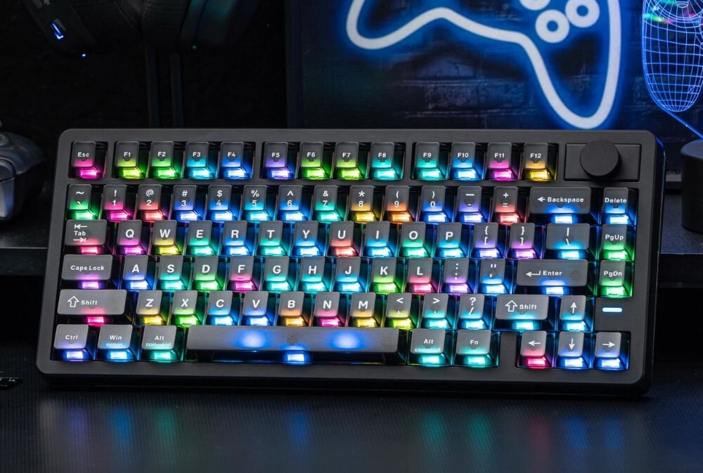Klawiatura mechaniczna z podświetleniem RGB, posiadająca klawisze z oznaczeniami liter i symboli. W tle widoczny jest neonowy kształt przypominający kontroler do gier.