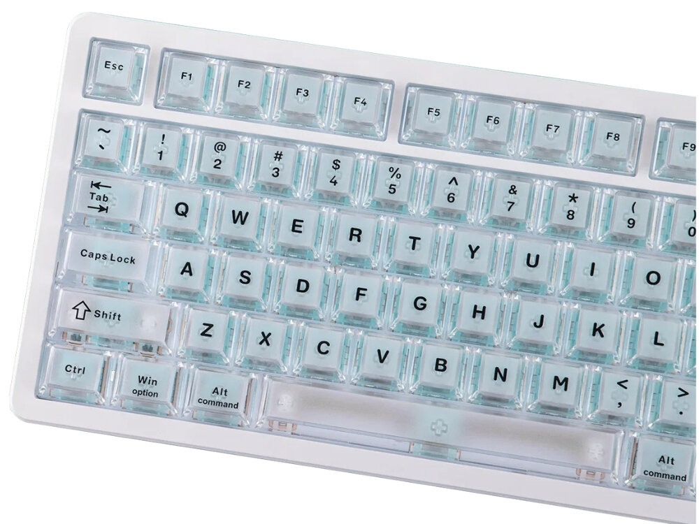 Klawiatura z przezroczystymi klawiszami, na których widoczne są oznaczenia takie jak Esc, F1-F8, QWERTY oraz inne standardowe klawisze. Klawisze mają białe tło z czarnymi literami i symbolami.