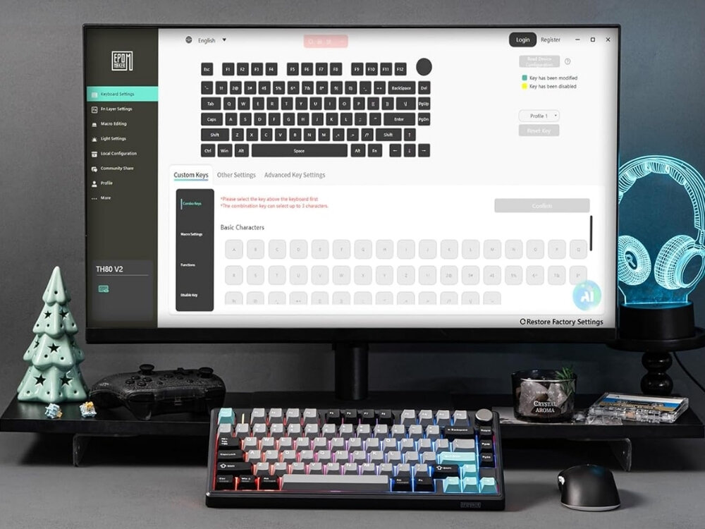 Na biurku znajduje się klawiatura z podświetleniem RGB oraz monitor z otwartym oprogramowaniem do konfiguracji klawiatury. Obok monitora widoczne są dekoracje w kształcie choinki i słuchawek, a także kontroler do gier.