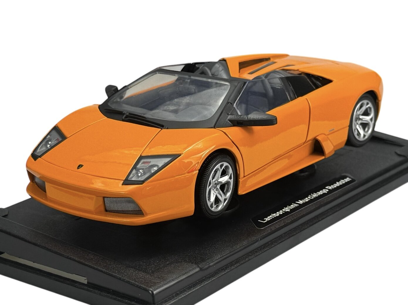 Pomarańczowy model samochodu Lamborghini Murcielago Roadster w skali 1:18, umieszczony na czarnej podstawce z napisem \'Lamborghini Murcielago Roadster\'.