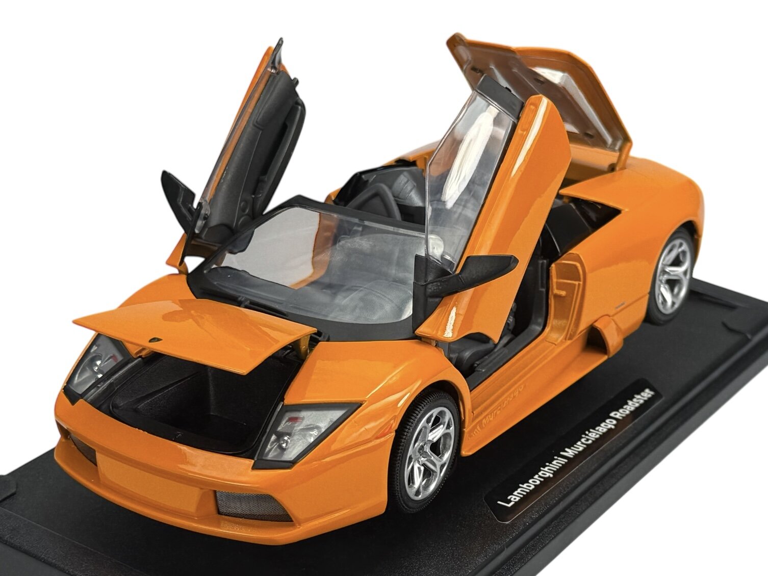 Pomarańczowy model samochodu sportowego z otwartymi drzwiami i maską, umieszczony na czarnej podstawce z napisem \'Lamborghini Murcielago Roadster\'.