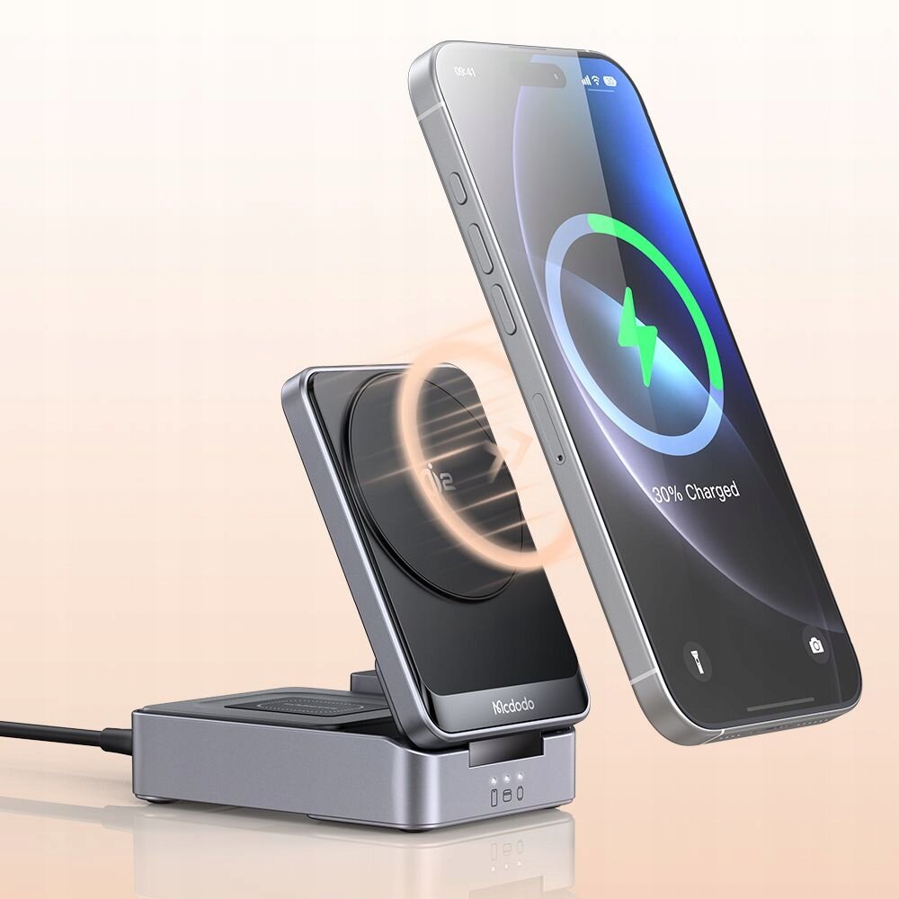Na obrazie widać stację dokującą Mcdodo z ładowarką indukcyjną, na której umieszczony jest smartfon z widocznym wskaźnikiem ładowania na ekranie. Na stacji widoczne jest logo \'Mcdodo\'.