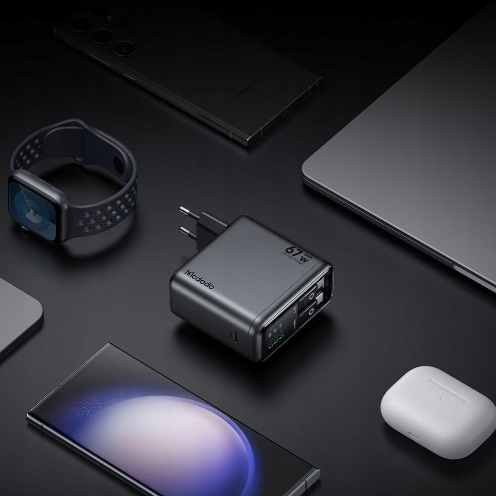Na ciemnym tle znajduje się ładowarka sieciowa z trzema portami USB-C, oznaczona jako \'Mcdodo\' i \'67W\'. Wokół niej rozmieszczone są różne urządzenia elektroniczne, takie jak smartfon, zegarek, laptop i słuchawki bezprzewodowe.