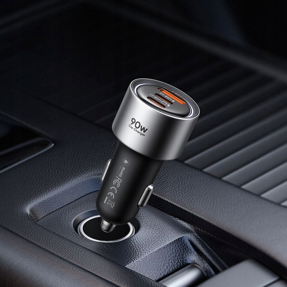 Na zdjęciu widoczna jest szybka ładowarka samochodowa z trzema portami: dwoma USB-C i jednym USB-A, z oznaczeniem \'90W Car Charger\'. Ładowarka jest umieszczona w gnieździe zapalniczki samochodowej.