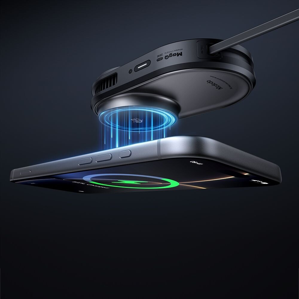 Obraz przedstawia uchwyt na telefon z funkcją ładowania indukcyjnego, unoszący się nad smartfonem. Na uchwycie widoczne są napisy \'Magsafe\' i \'Mcdodo\'.