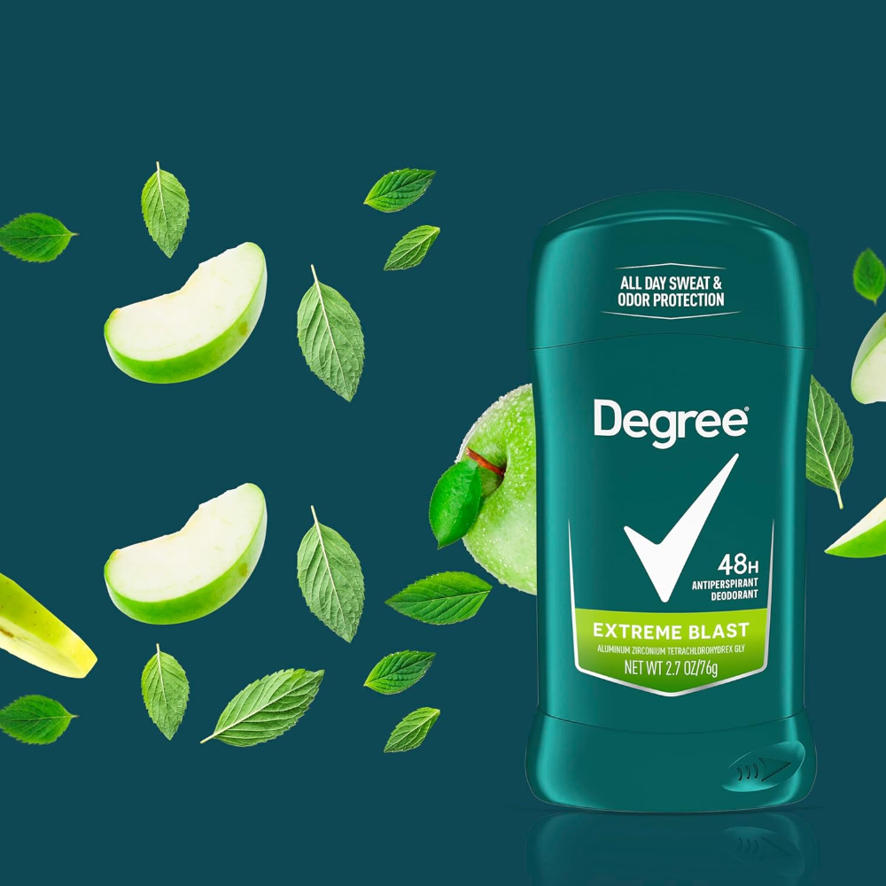 Na ciemnym tle znajduje się zielony antyperspirant w sztyfcie z napisem \'Degree 48H Antiperspirant Deodorant Extreme Blast\'. Wokół produktu widoczne są kawałki zielonego jabłka i zielone liście.