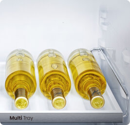 W lodówce znajdują się trzy butelki białego wina leżące na półce oznaczonej jako \'Multi Tray\'.