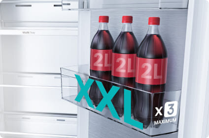 W lodówce znajdują się trzy butelki napoju o pojemności 2L każda, umieszczone w przezroczystej półce. Na obrazie widoczny jest napis \'XXL x3 MAXIMUM\'.