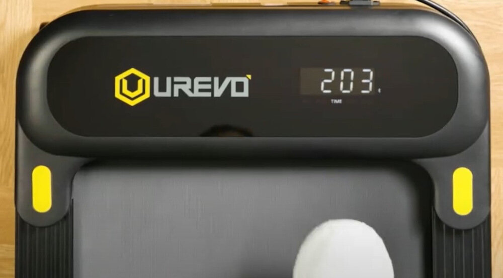 Na zdjęciu widoczna jest bieżnia elektryczna z logo \'UREVO\' oraz wyświetlaczem pokazującym \'2.03 TIME\'.