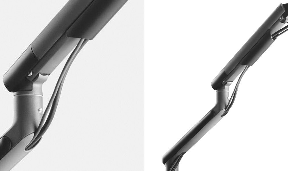 Zdjęcie przedstawia czarny uchwyt do monitora z widocznymi elementami montażowymi i przewodami. Uchwyt ma nowoczesny design z metalicznymi i plastikowymi elementami.