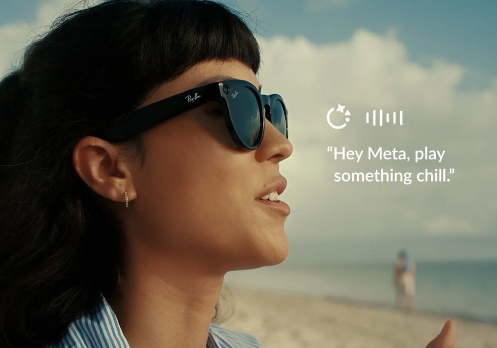 Osoba nosi czarne okulary przeciwsłoneczne z widocznym logo Ray-Ban. Obok znajduje się tekst: \'Hey Meta, play something chill.\'