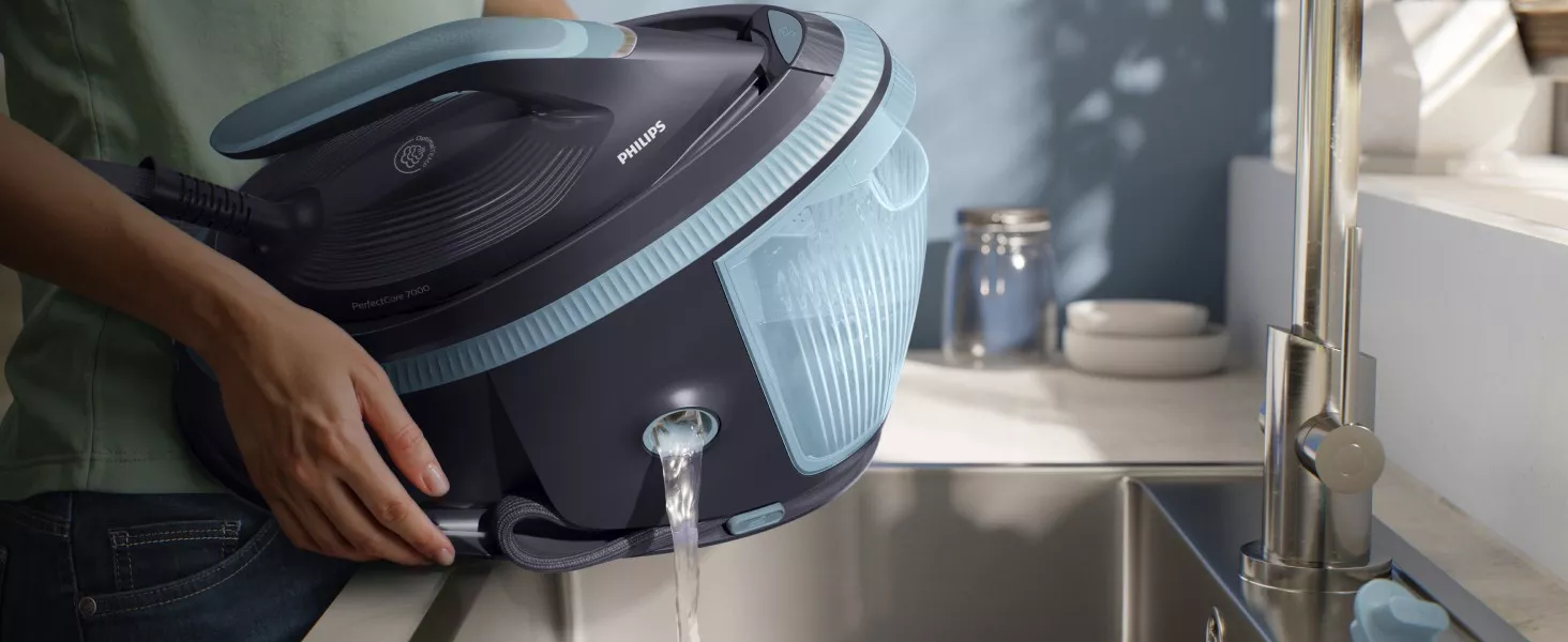 Osoba trzyma generator pary marki PHILIPS nad zlewem, z którego wylewa się woda. Na urządzeniu widoczne są napisy \'PHILIPS\' i \'PerfectCare 7000\'.