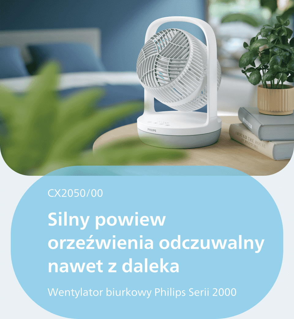 Na zdjęciu znajduje się biały wentylator biurkowy marki Philips, umieszczony na drewnianym stole obok stosu książek i rośliny w doniczce. Tekst na obrazie: \'CX2050/00 Silny powiew orzeźwienia odczuwalny nawet z daleka Wentylator biurkowy Philips Serii 2000\'.