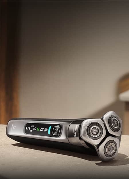 Na obrazie widoczna jest elektryczna golarka z trzema okrągłymi głowicami tnącymi i wyświetlaczem z ikonami. Na obudowie znajduje się logo \'Philips\'.