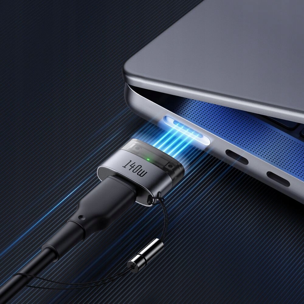 Obraz przedstawia magnetyczny adapter podłączony do portu laptopa, z widocznym napisem \'140W\' na adapterze. Widać niebieskie światło emitowane z portu laptopa.