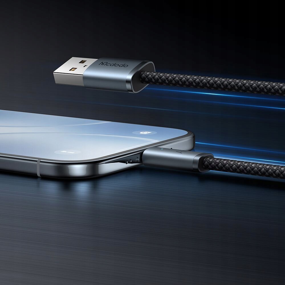 Obraz przedstawia kabel USB z wtyczką USB-A i USB-C podłączony do smartfona. Na wtyczce USB-A widoczne jest logo \'Mcdodo\'.
