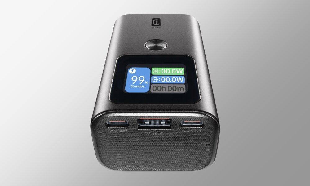 Na obrazie widoczny jest antracytowy powerbank z wyświetlaczem pokazującym 99% naładowania i czas 00h 00m. Poniżej znajdują się trzy porty USB z oznaczeniami IN/OUT 30W i OUT 22.5W.