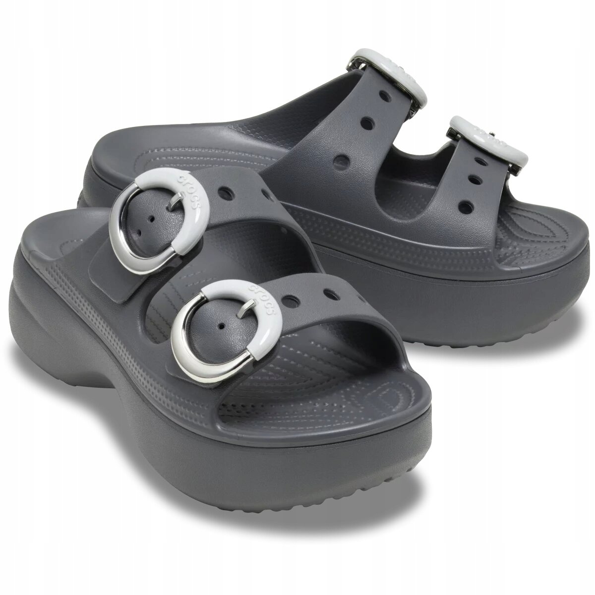 Para szarych klapków na platformie z dwoma paskami, każdy z dużą, okrągłą klamrą. Na klamrach widoczny jest napis \'Crocs\'.