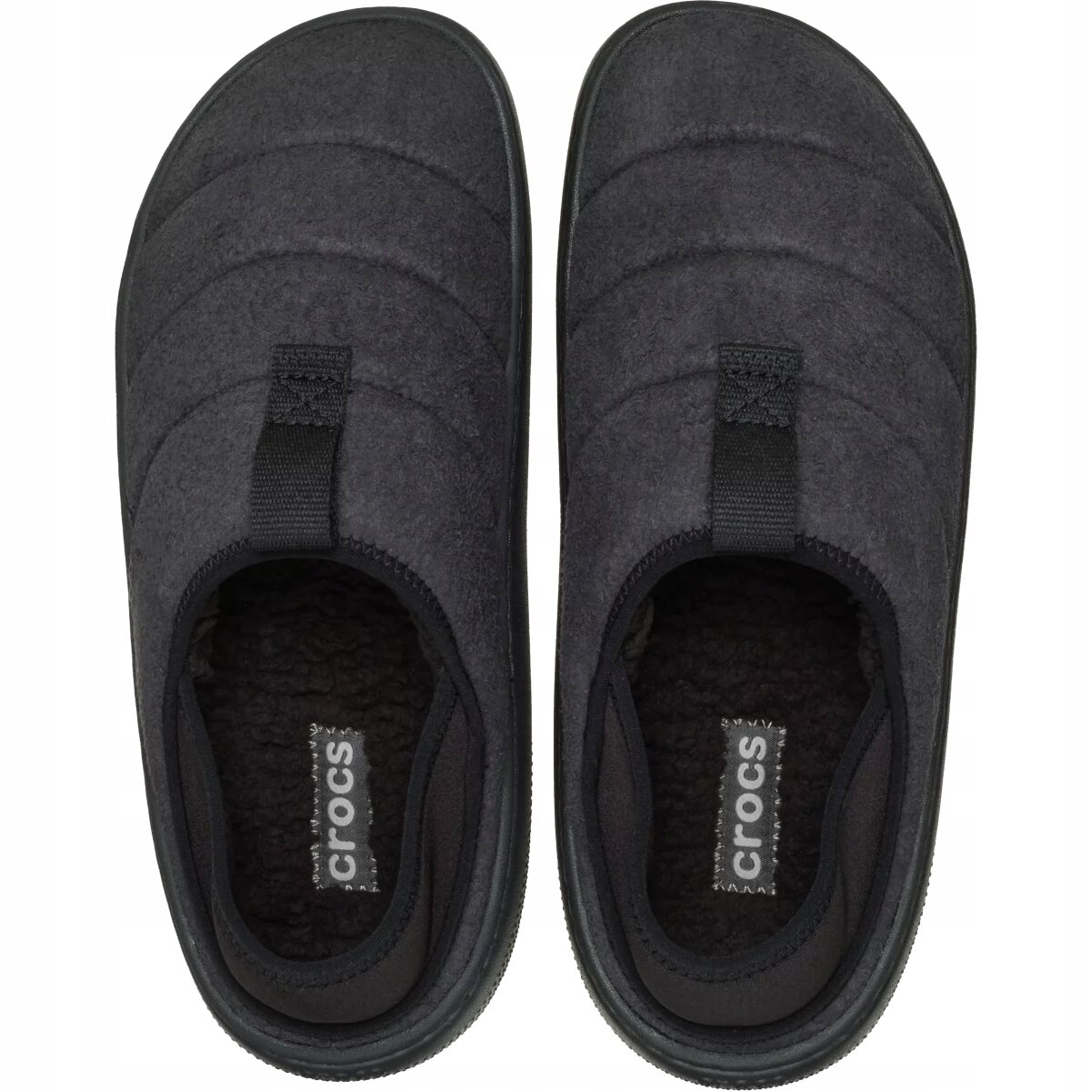 Para ciemnoszarych kapci z widocznym logo \'crocs\' na wkładce. Kapcie mają miękką, pikowaną powierzchnię i elastyczne wstawki na podbiciu.