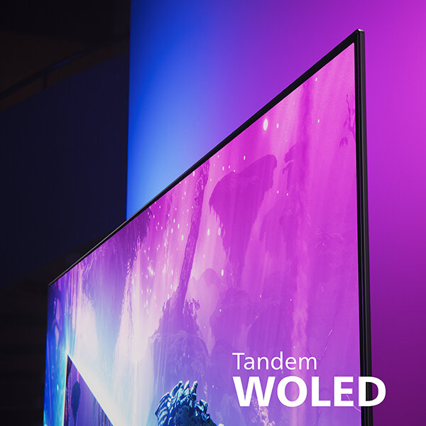 Zbliżenie na ekran telewizora z wyświetlanym kolorowym obrazem, z efektem świetlnym na ścianie. Widoczny tekst: \'Tandem WOLED\'.