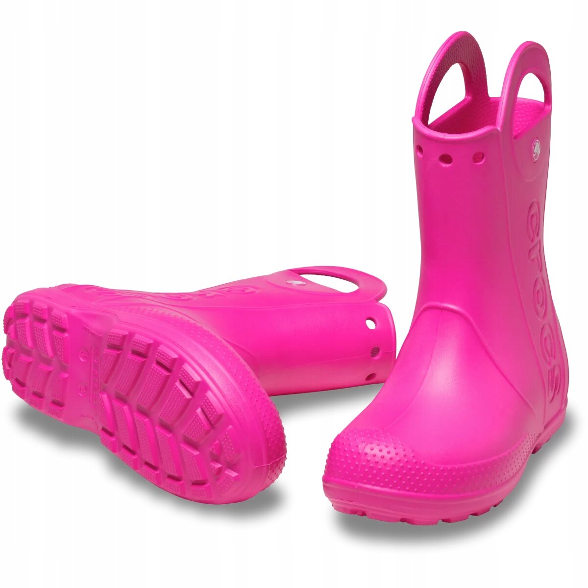 Różowe dziecięce kalosze z uchwytami na górze i wyraźnym bieżnikiem na podeszwie. Na boku widoczne jest logo \'crocs\'.