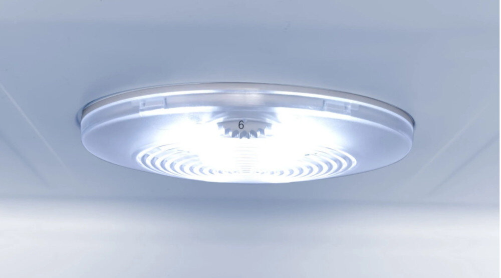 Na obrazie widoczna jest okrągła, biała lampa LED zamontowana na suficie wnętrza lodówki. Na środku lampy znajduje się liczba \'6\'.