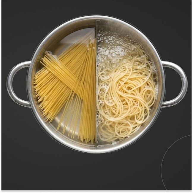 Garnek z makaronem spaghetti, z jednej strony surowym, a z drugiej ugotowanym, stoi na ciemnej powierzchni.