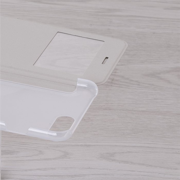 Przezroczyste etui na telefon z klapką, która ma wycięcie na ekran i otwór na głośnik. Etui leży na jasnym, drewnianym tle.