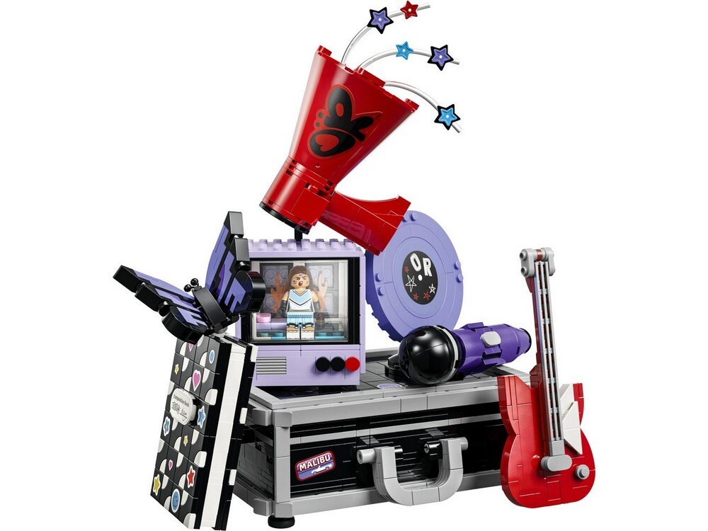 Zestaw LEGO przedstawia kolorową scenę z elementami muzycznymi, w tym gitarą, megafonem i ekranem z minifigurką. Na walizce widoczne są naklejki z napisami \'MALIBU\' i \'O R\'.